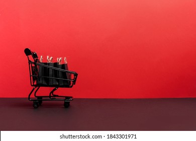 black paper bags in shopping cart on red background, copy space. black friday concept - Shutterstock ID 1843301971