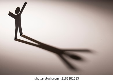 Black Paper Cutout In Hand Up Figure Shape Stand On Light With Shadow On White Background, In Concept Of Business, Weakness And  Corruption.