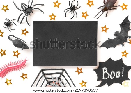 Black paper sheet on Halloween background with bats, spiders and golden stars. Modern Holiday Mock up. Halloween party invitation. Flat lay, top view, copy space. Thanksgiving fall decoration. 