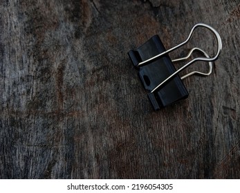A black paperclip is placed sideways. Paperclip on a wooden background.