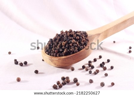 Black papper in spoon isolate on white background