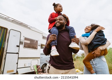 Black parents laughing while playing with their children by trailer outdoors