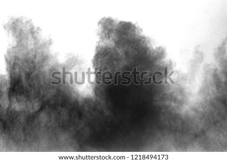 Black particles splatter on white background. Black powder dust exploding.

