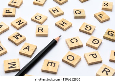 Black Pencil And Scattered Alphabet Letters On Wooden Blocks On White Background