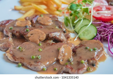 Black Pepper Steak In Dish With Tomato, French Fries, And Portobello Mushroom In Sauce Gravy.