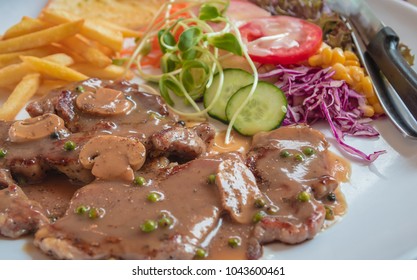 Black Pepper Steak In Dish With Tomato, French Fries, And Portobello Mushroom In Sauce Gravy.