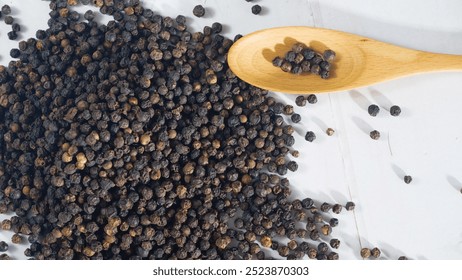 Black peppercorns scattered on a white wooden surface with a wooden spoon, showcasing spices for cooking, in a clean and minimal food presentation - Powered by Shutterstock