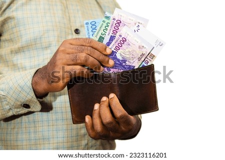 Black person Holding brown wallet
With West African CFA franc notes, hand removing money out of wallet over white background removing money from wallet