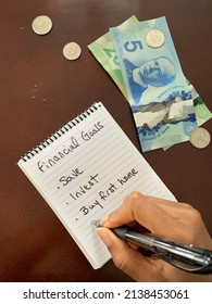 A Black Person Holding A Pen And Writing A Financial Goals List Surrounded By Canadian Currency