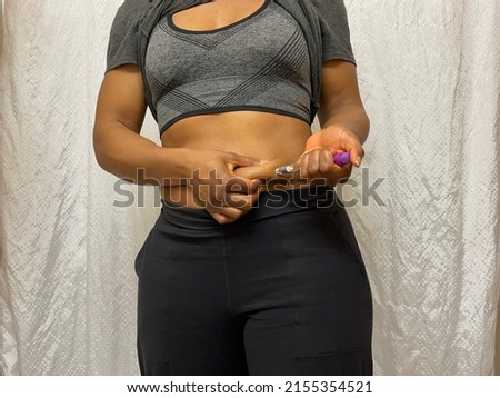 A Black person injecting their abdomen with medication into their subcutaneous layer for diabetes or fertility treatments