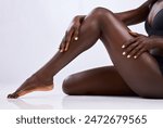 Black person, legs and skincare in studio for hair removal, epilation and smooth skin on white background. Body, woman and hands touching with manicure for wellness, waxing or moisturize and beauty