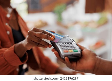 Black person using credit card to make contactless payment for fresh organic produce at a local market. Closeup of african american customer doing cashless transaction at grocery store - Powered by Shutterstock