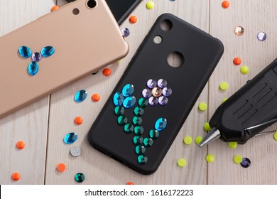 Black Phone Case Decorated With Rhinestone Flower, Top View. Beautiful Result Of Child's DIY Project.