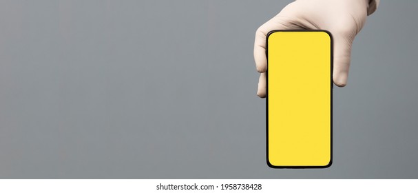 Black Phone In Doctor Hand With Yellow Screen For Mockup, Gray Background