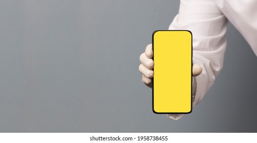 Black Phone In Doctor Hand With Yellow Screen For Mockup, Gray Background