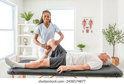 A black Physiotherapist helping senior man with in clinic. Elderly man undergoing physiotherapy treatment for injury - Powered by Shutterstock