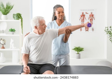 A black Physiotherapist helping senior man with in clinic. Elderly man undergoing physiotherapy treatment for injury - Powered by Shutterstock