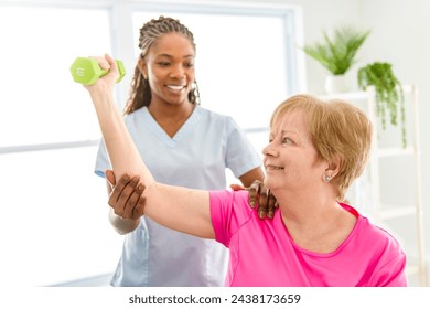 A Black physiotherapist helping senior woman in clinic. Elderly woman undergoing physiotherapy treatment for injury - Powered by Shutterstock