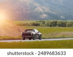 Black pickup crew cab truck on a countryside road at sunset