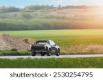 Black pickup truck driving through a scenic rural area