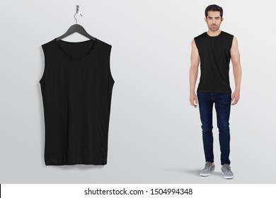 Black Plan Sleeveless Shirt On A Man Male Model In Black Denim Jeans Pant, Isolated, Mockup. Hanging Black Blank Sleeveless Shirt Shirt, Against Empty Wall.