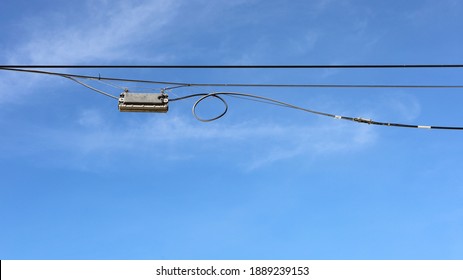 A Black Plastic Box Is Hung On The Wires. Fiber Optic Splitter Box (Plc, Coupler) For Fiber Optic Splitter Of High Speed Internet. On A Blue Sky Background With A Copy Space. Selective Focus