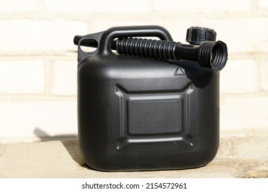 Black plastic canister for gasoline with funnel on a brick wall background