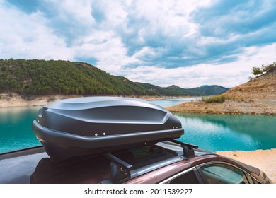 Black Plastic Car Rooftop Cargo Box Or Roof Carrier For Traveling. Removable Storage Container Mounted On Car Roof Rack. Beautiful Nature Background.