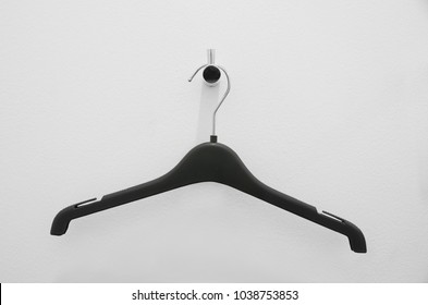 Black plastic cloth hanger on white painted wall in fitting room with clipping path 