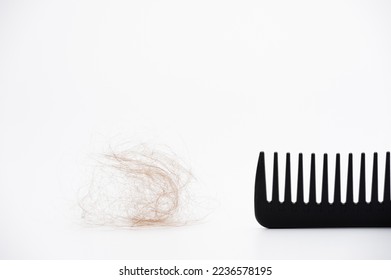 peine negro de plástico con pelo perdido en el fondo blanco
