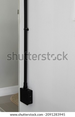 The black plastic electrical junction box on white concrete wall.
