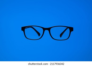 Black Plastic Frame Eyeglasses. Close Up Studio Shot, Isolated On Blue Background, No People.