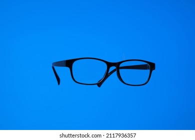 Black Plastic Frame Eyeglasses. Close Up Studio Shot, Isolated On Blue Background, No People.