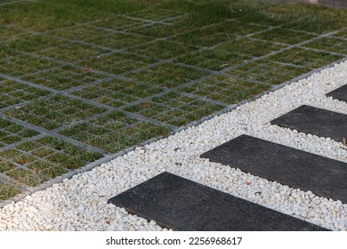 black plastic grid with green grass for the cars and white decorative stones for the path - Shutterstock ID 2256968617