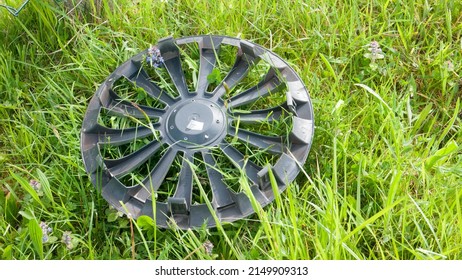 Black plastic hubcap in a green grass field