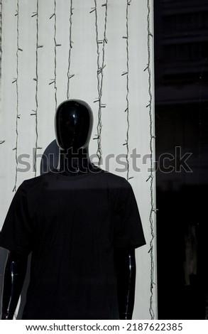 a black plastic mannequin in a T-shirt on a shop window. men's fashion