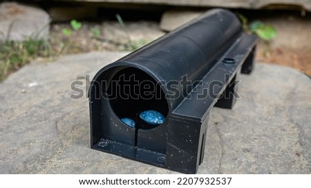 A black plastic rat trap on concrete floor. bait poison box for rat. A black plastic rat trap (baiting box). Pest control concept image.