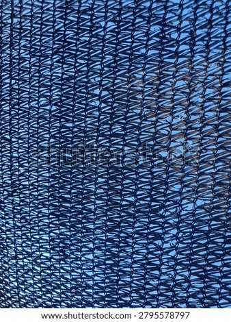 Black plastic shading net texture background. Mesh greenhouse paranet with blue sky background.