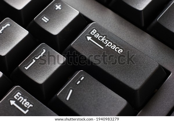 Black plastic standard\
English computer keyboard close up macro shot top side view\
backspace button.