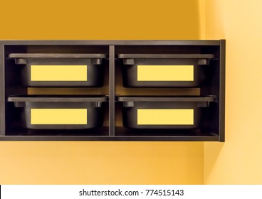 Black Plastic Storage Bin With Yellow Label For Room Organizer Against Yellow Wall.