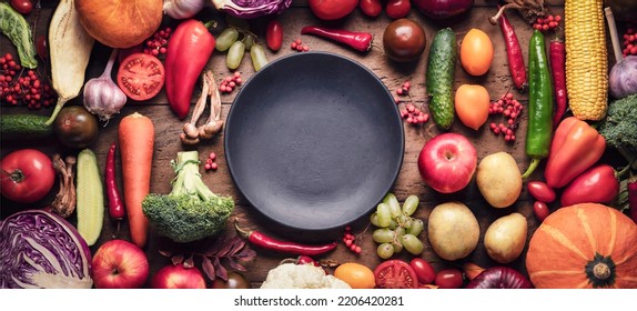 Black plate on the table with fruits and vegetables, fresh autumn harvest on a rustic wooden background top view. assortment of vegetables for healthy food, panoramic photo, copy space concept - Powered by Shutterstock