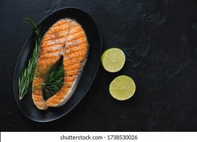 Black Plate With Roasted Salmon Steak Over Black Stone Background, Horizontal Shot With Copy Space, Above View