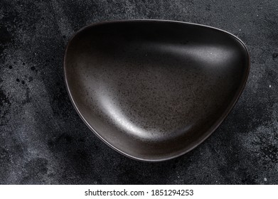 Black plate triangular shape on textured black background. Top view. Copy space