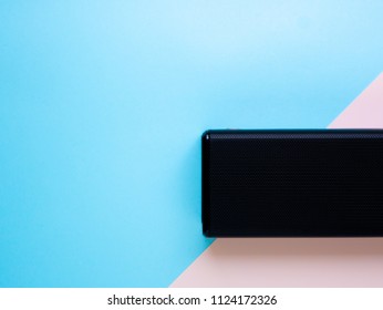 Black portable speaker wireless on blue and pink pastel color background. Flat lay, Top View