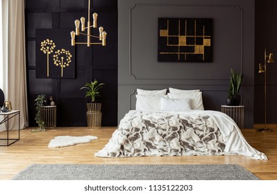 Black Poster On Grey Wall Above Bed With White Pillows In Dark Bedroom Interior With Plants. Real Photo