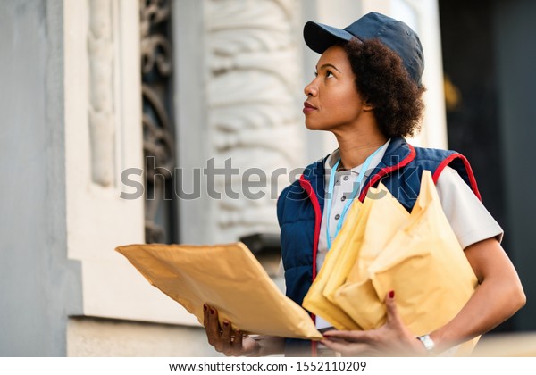 Black\
postwoman delivering mail in residential district.\
