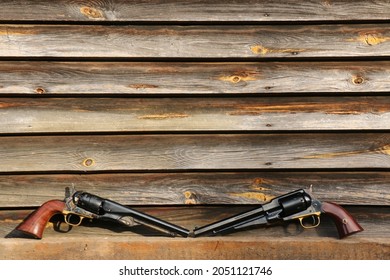 Black powder revolvers on the background of an old wall made of boards.