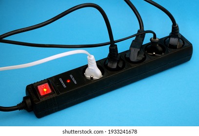 Black Power Surge Protector With Cables And Light On Blue Background. Electrical Power Strip Extension Socket, Power Extender, Surge Protector Isolated On Blue Background.