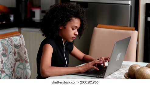 Black Preteen Girl Using Laptop At Kitchen. Child Browsing Internet