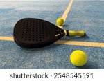 Black professional paddle tennis racket and ball with natural lighting on blue background. Horizontal sport theme poster, greeting cards, headers, website and app